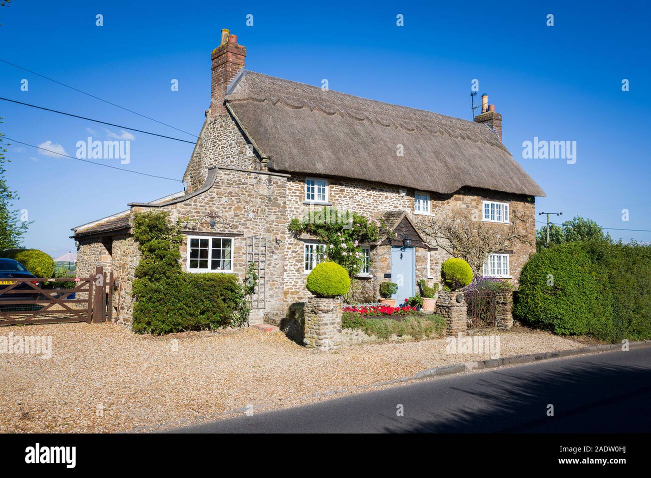 A pretty detached thatched cottage on the roadsise through Sandy Lane village in the Parish of Bromham and Chittoe Wiltshire England UK Stock Photo