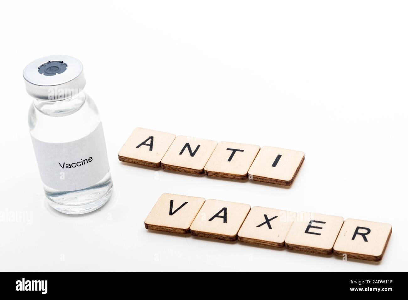 Vaccine concept showing a medical vial with a Vaccine label on a white background along with a sign reading Anti Vaxer Stock Photo