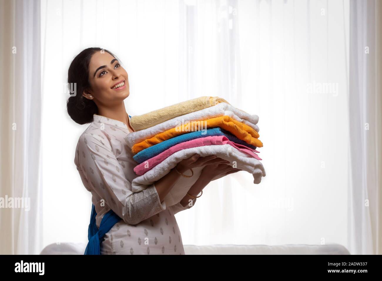 Portrait of a single woman carrying folded clothes in her hand. Stock Photo