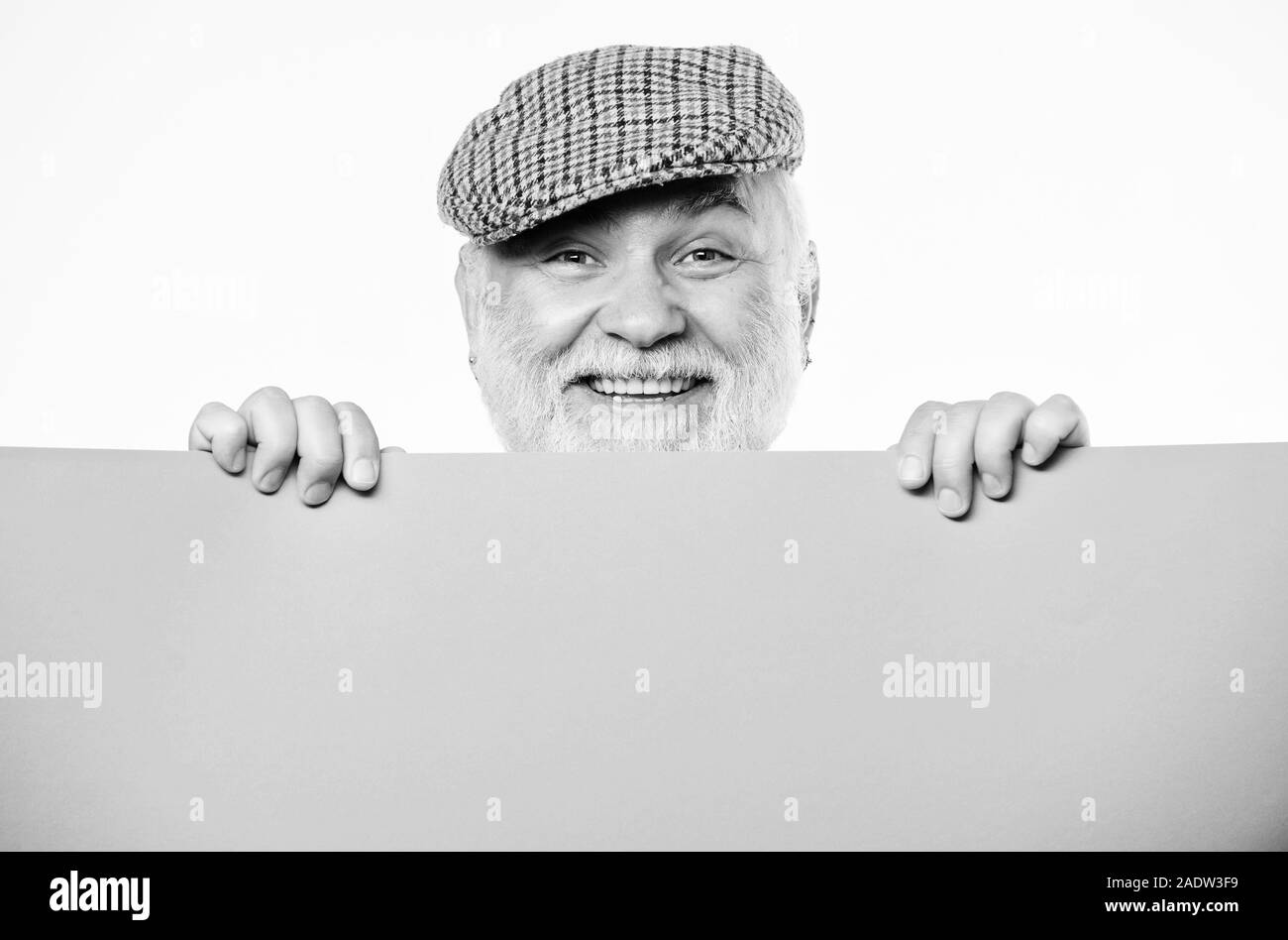 Senior bearded man peeking out of banner place information. Announcement concept. Public information. Advertisement elderly people. Pensioner hold poster information copy space. Weekend entertainment. Stock Photo