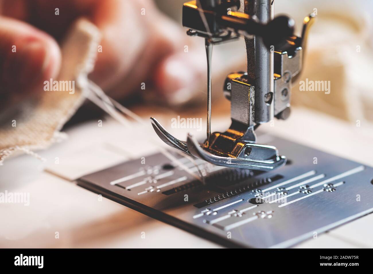hand is holding the lower thread behind the presser foot of a sewing