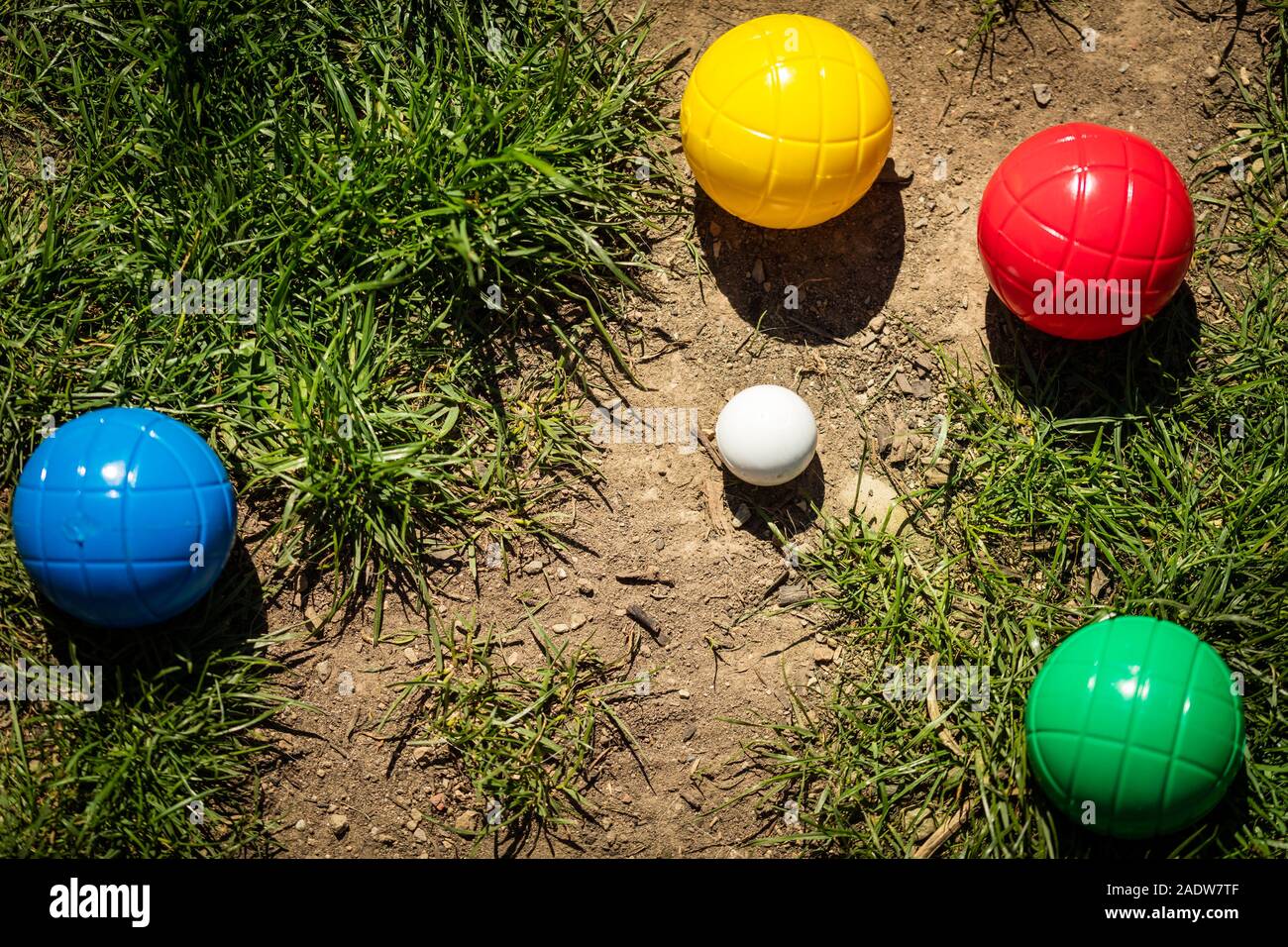 a lot of colorful plastic boules or boccia balls are lying on a green meadow in the summer Stock Photo