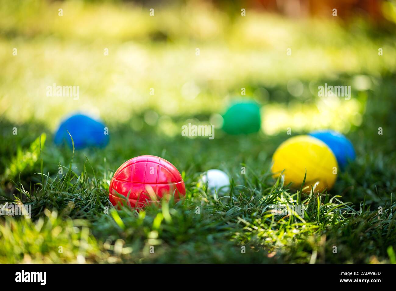 a lot of colorful plastic boules or boccia balls are lying on a green meadow in the summer Stock Photo