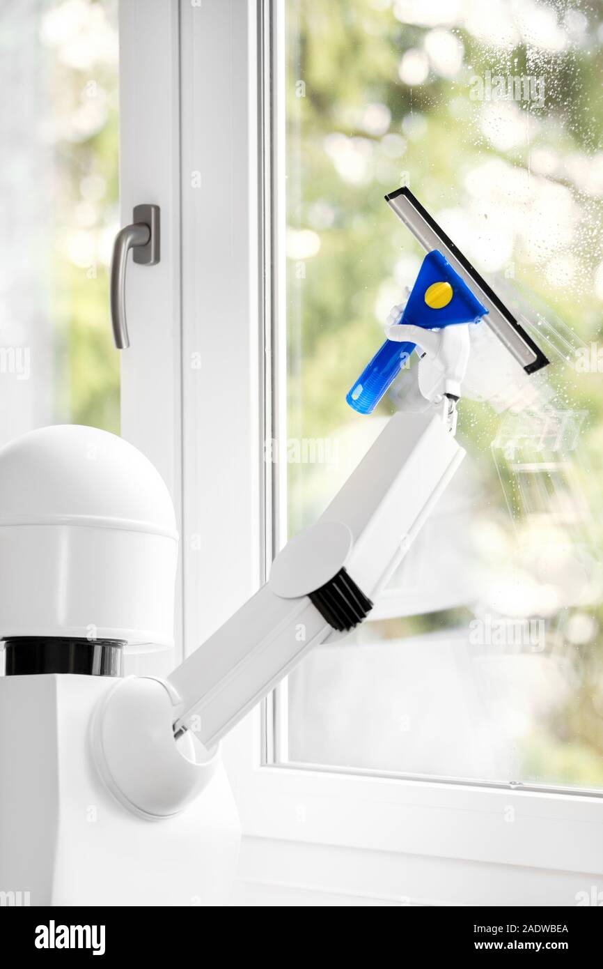 a autonomous robot is washing a window with a tool, using his robot hand for the routine job Stock Photo