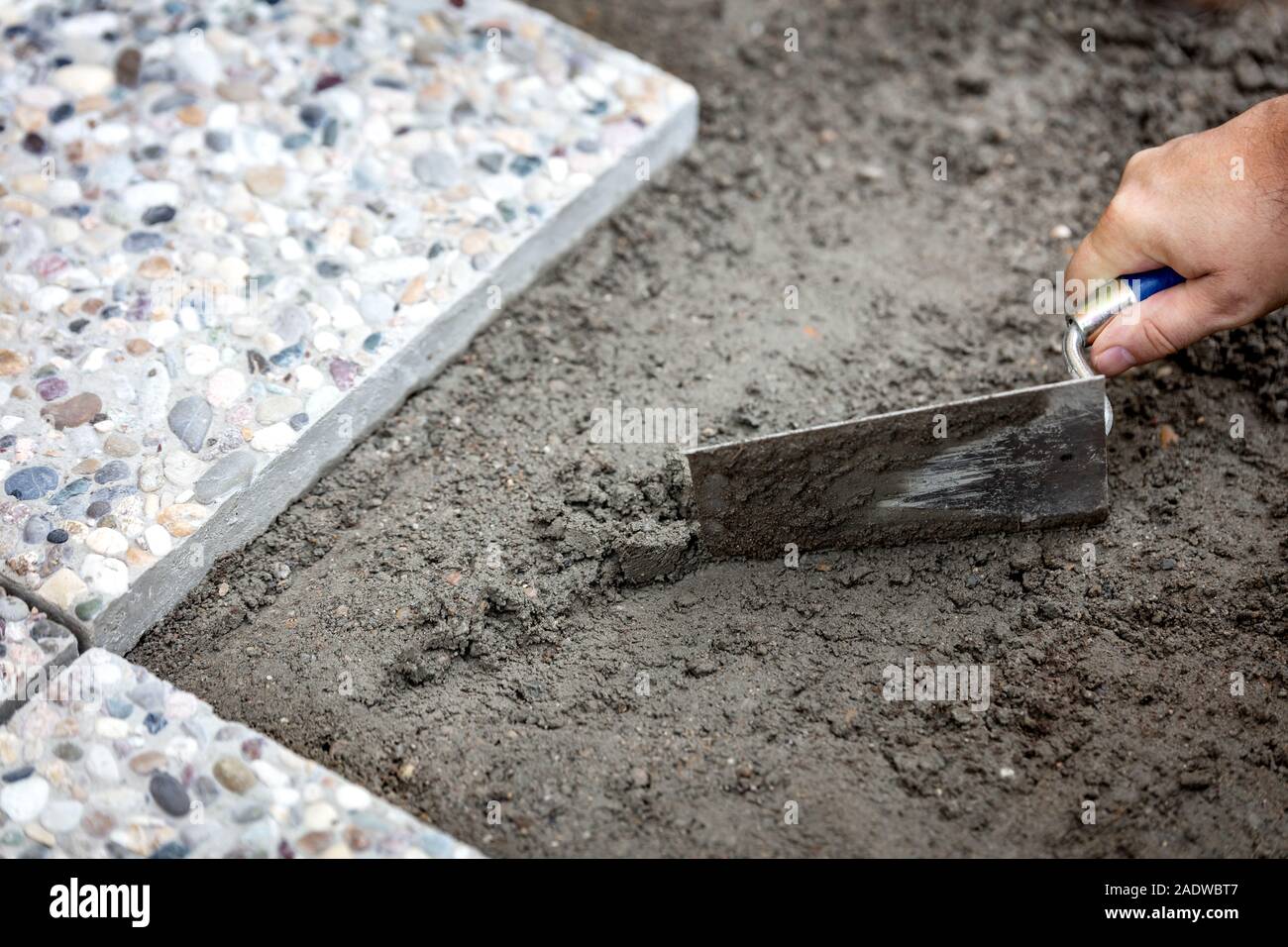 Man laying concrete slabs in fresh mortar, craftsman applying trowel mortar to lay floor Stock Photo