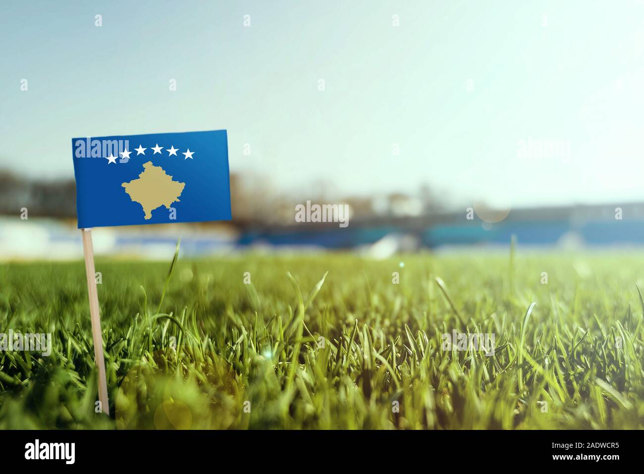 Miniature stick Kosovo flag on green grass, close up sunny field. Stadium background, copy space for text. Stock Photo