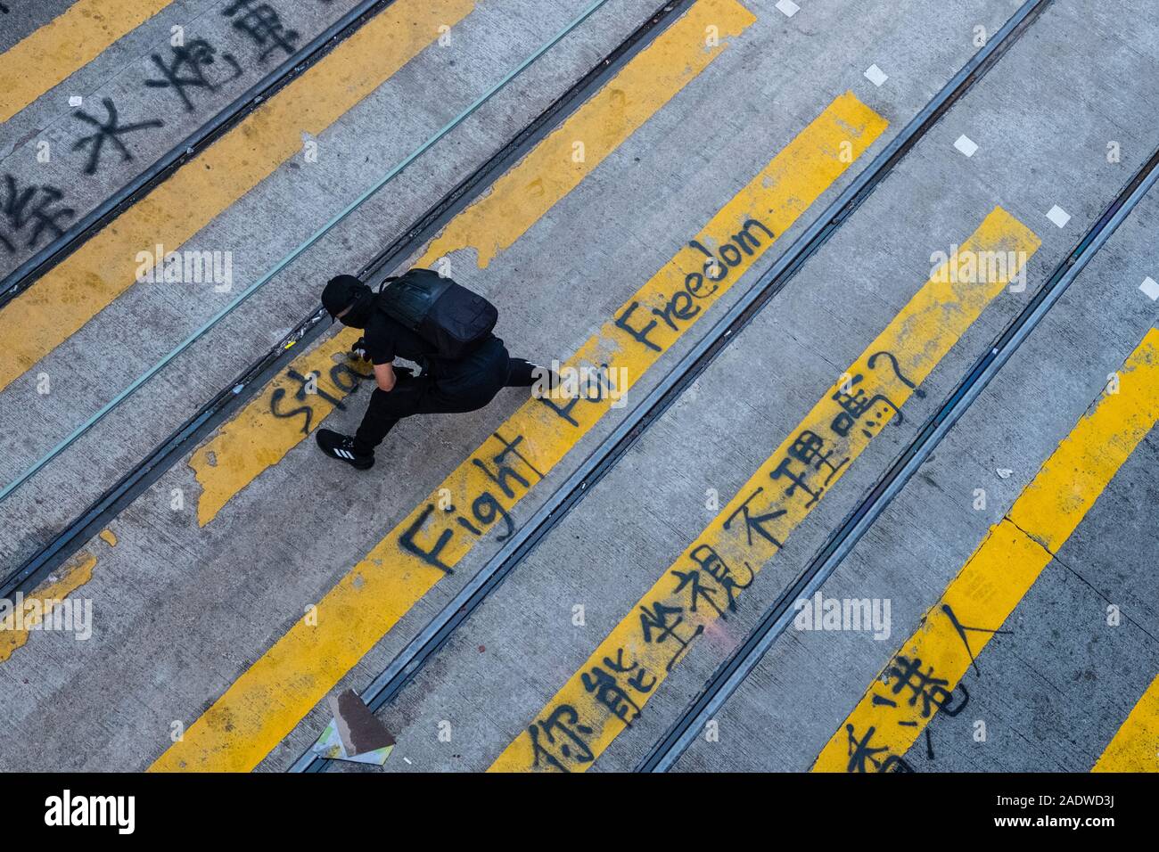 HongKong - November, 2019: Protester writes graffiti on pedestrian crossing during the 2019 HongKong protests, a series of demonstrations in Hongkong started as the Anti-Extradition Law Amendment Bill (Anti-ELAB) movement. Stock Photo