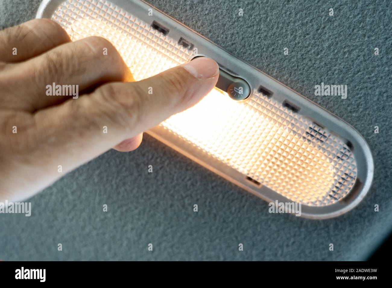 Turn on the lamp with the button. Closeup photo of hands man turning light on in car salon. Stock Photo