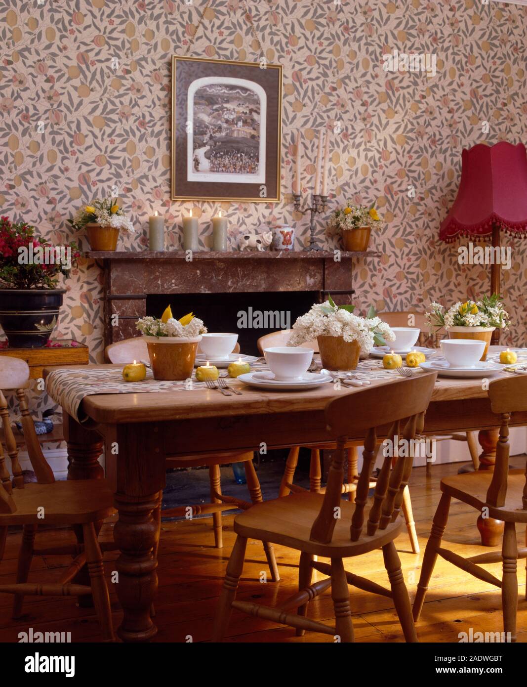 Pine chairs and table set for lunch in a traditional dining room with fruit  patterned wallpaper Stock Photo - Alamy