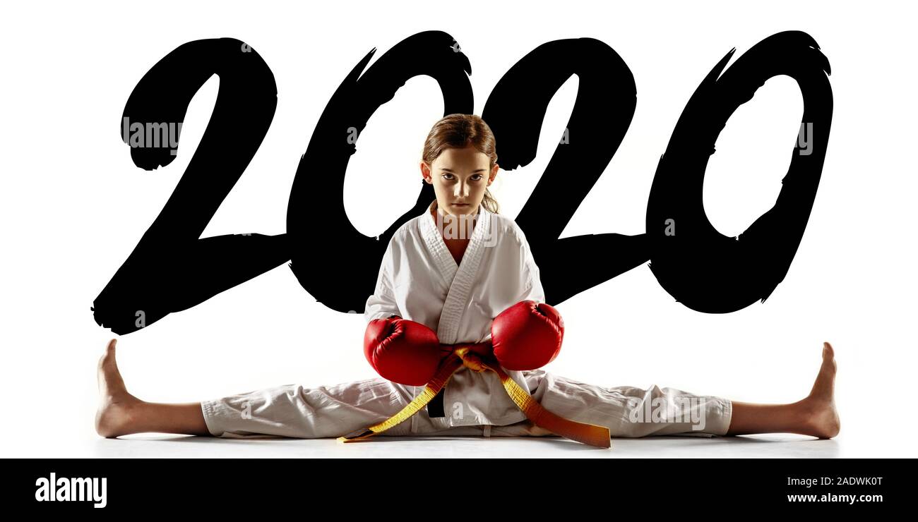 Confident junior in kimono practicing hand-to-hand combat, martial arts. Young female fighter with yellow belt's training on white studio background. Concept of healthy lifestyle, sport. Flyer, 2020. Stock Photo