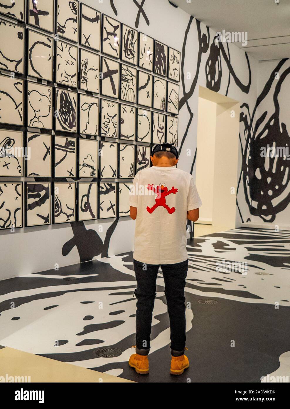 Man standing by art by Brian Donnelly aka KAWS sculptor and graffiti