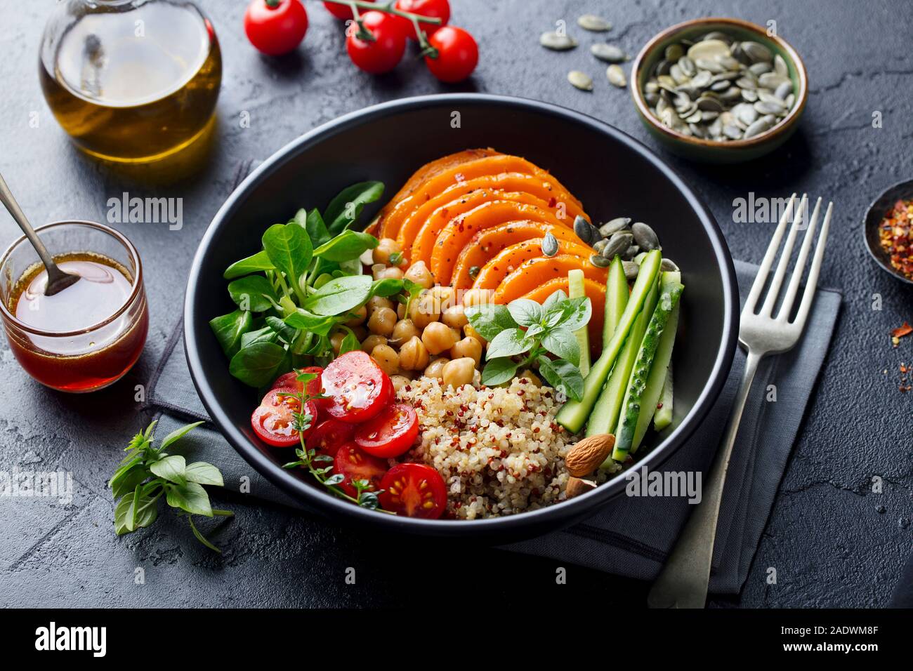 Healthy vegetarian salad. Roasted pumpkin, quinoa, tomatoes, green salad. Buddha bowl. Slate background. Close up. Stock Photo