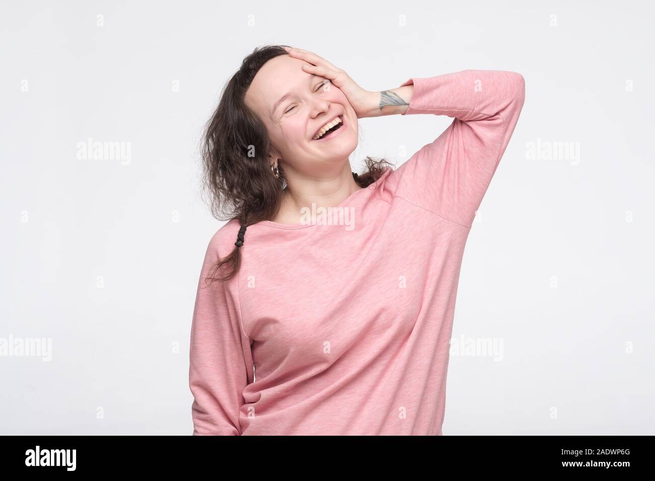 Caucasian pretty woman in pink pullover laughing on joke or is glad that she remembered important fact. studio shot Stock Photo