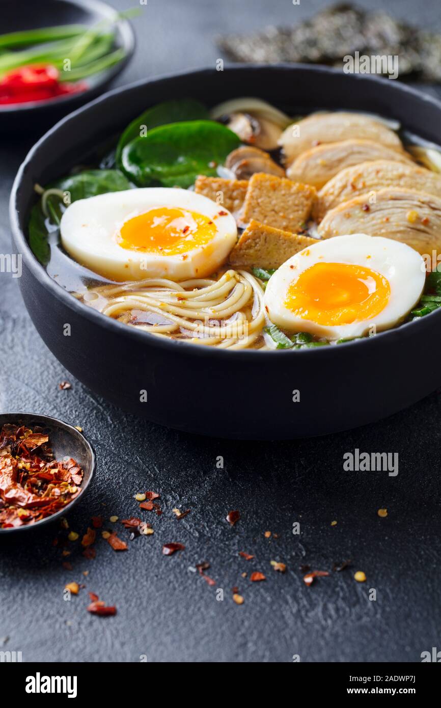 Asian noodle soup, ramen with chicken, tofu, vegetables and egg in bowl. Slate background Stock Photo