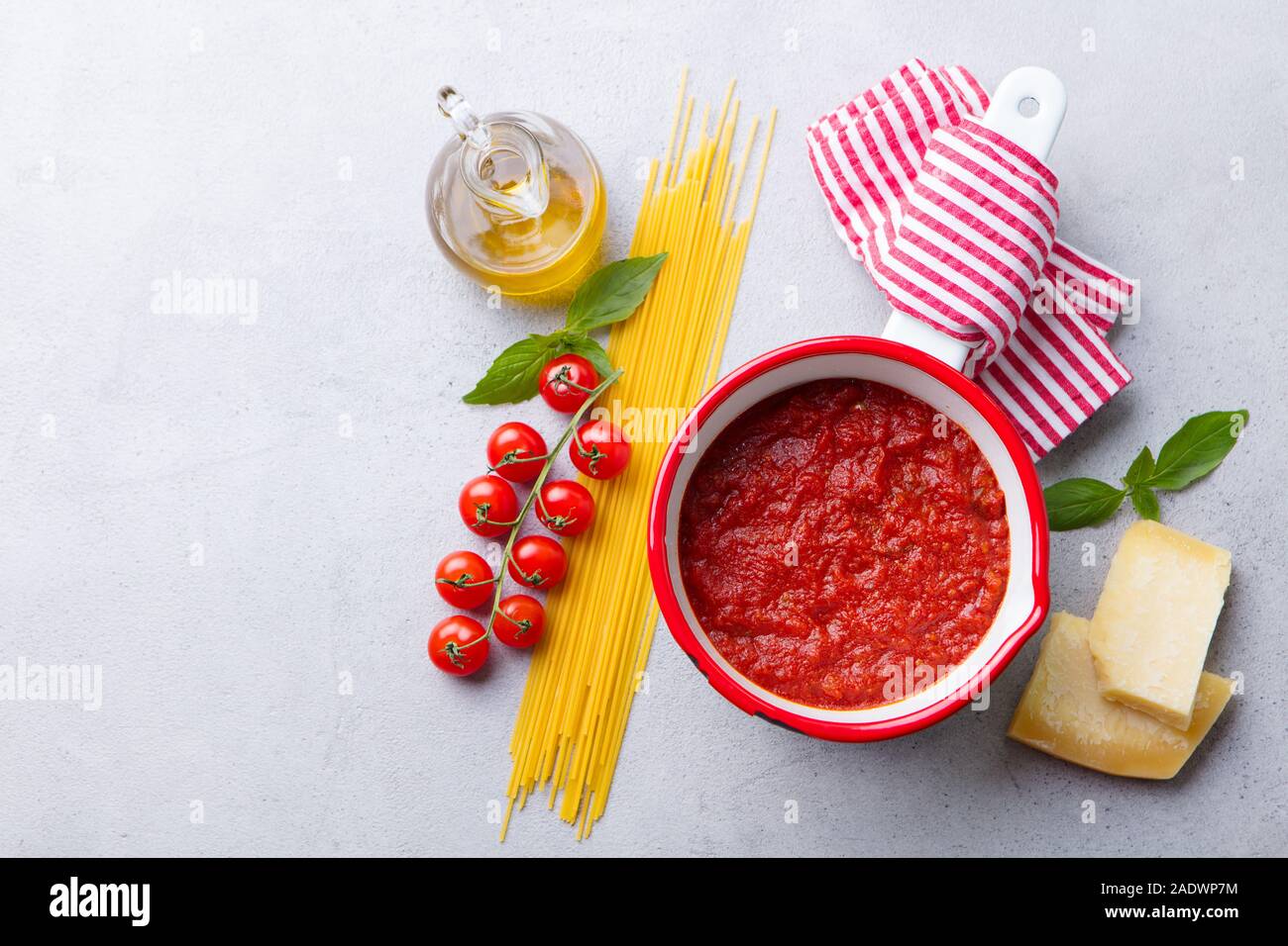 Traditional tomato sauce in saucepan with spaghetti pasta. Grey background. Copy space. Top view