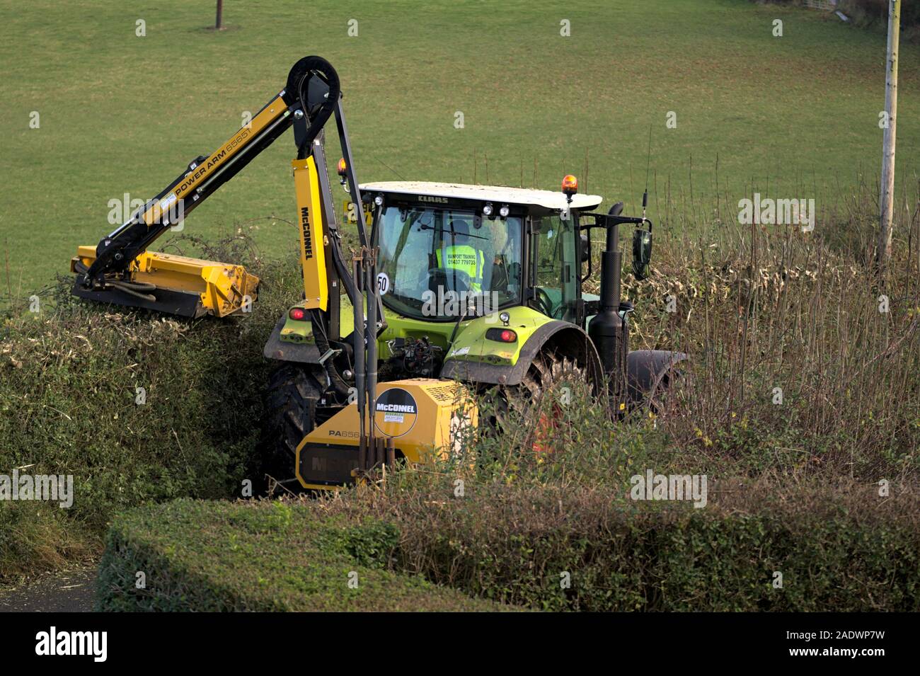 Aberystwyth Ceredigion Wales/UK December 04 2019: Yellow Tractor hedge cutting on a rural country lane Stock Photo