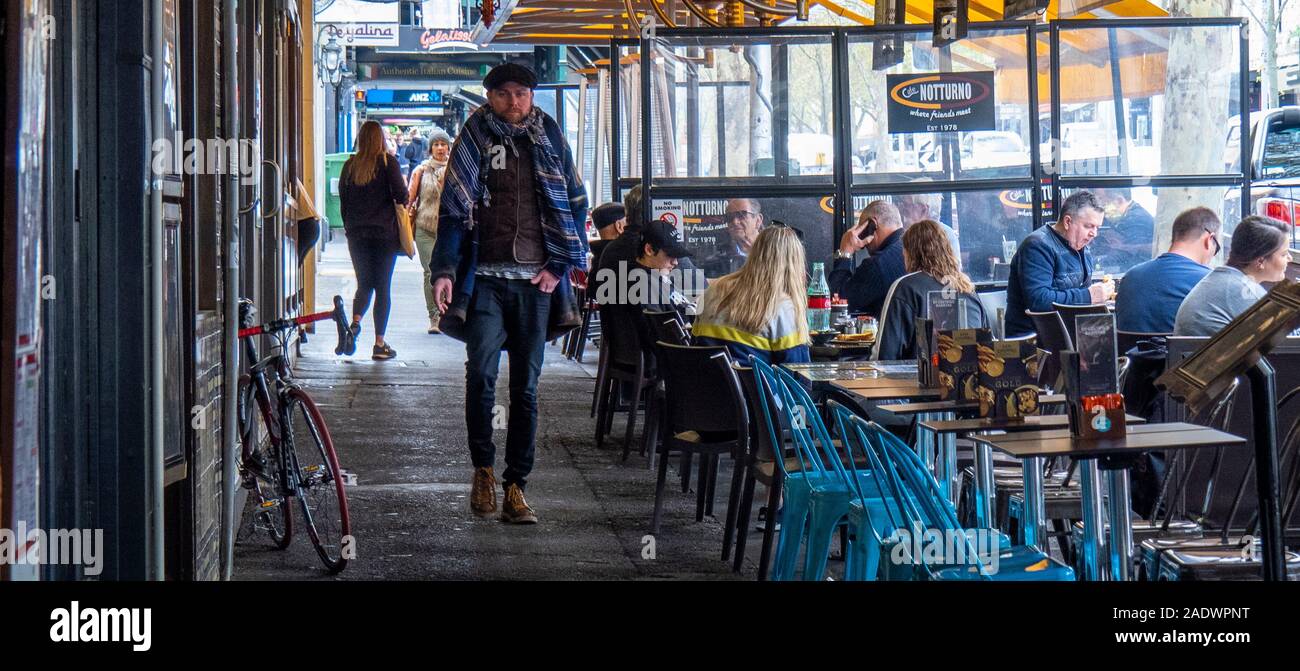 Man walking along Lygon Street popular for alfresco dining Carlton Melbourne Victoria Australia. Stock Photo