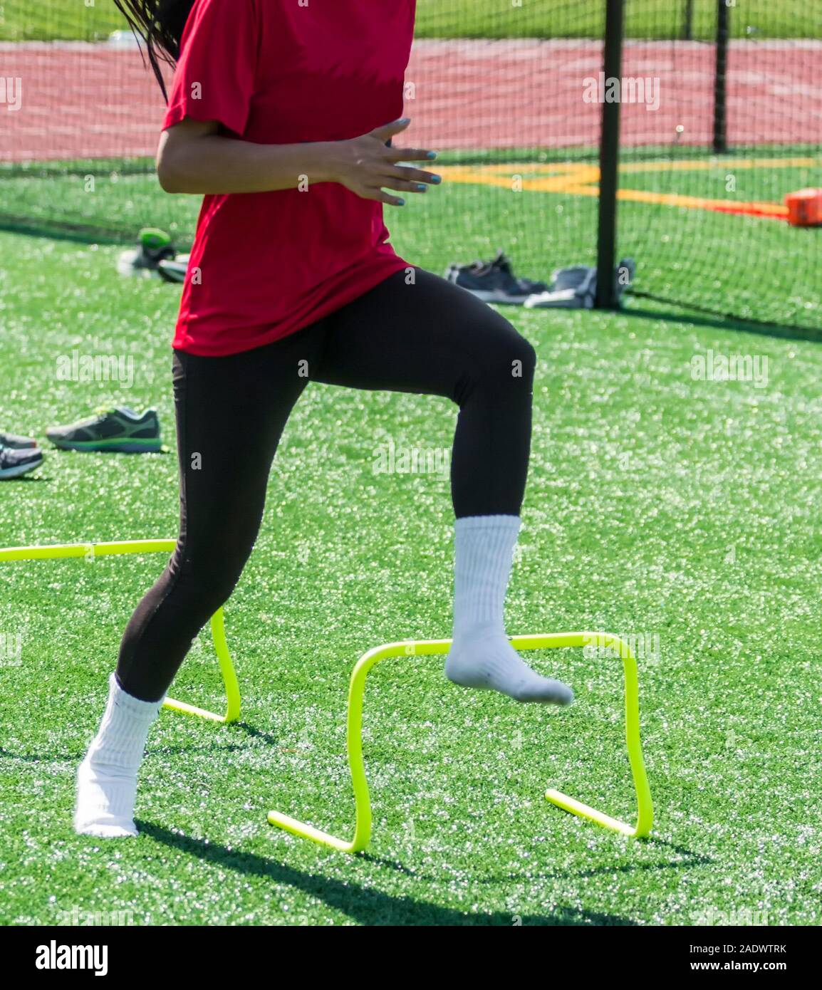 A high school girl is performing speed drills with no shoes on over