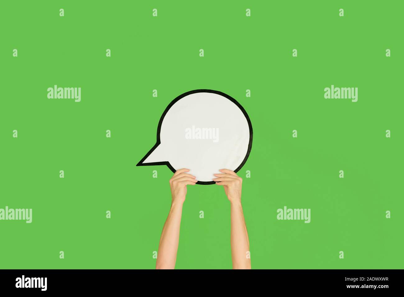Hands holding the sign of comment on green studio background. Negative ...