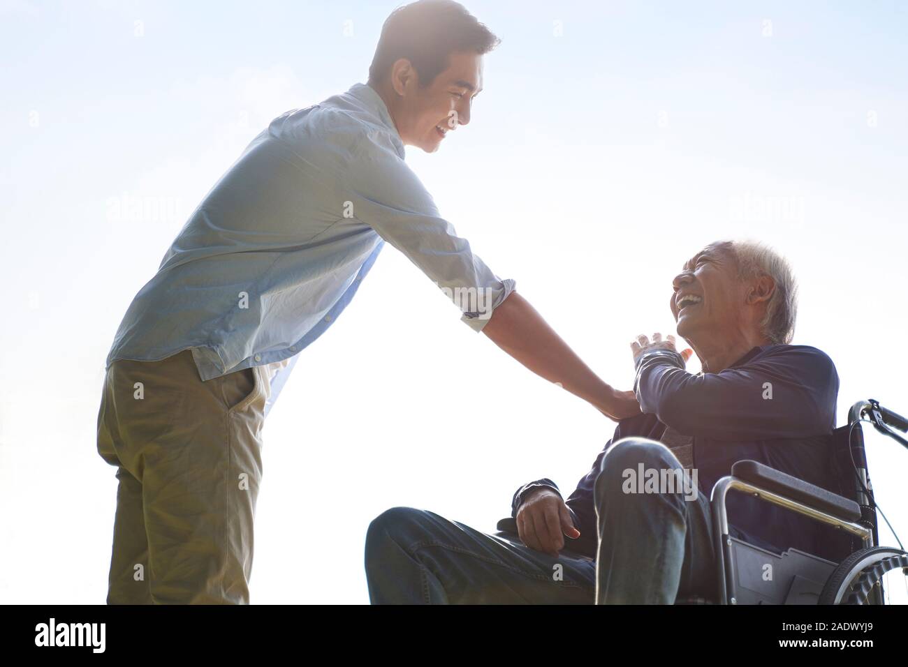 young asian adult son giving dad a pat on the shoulder, happy and smiling Stock Photo