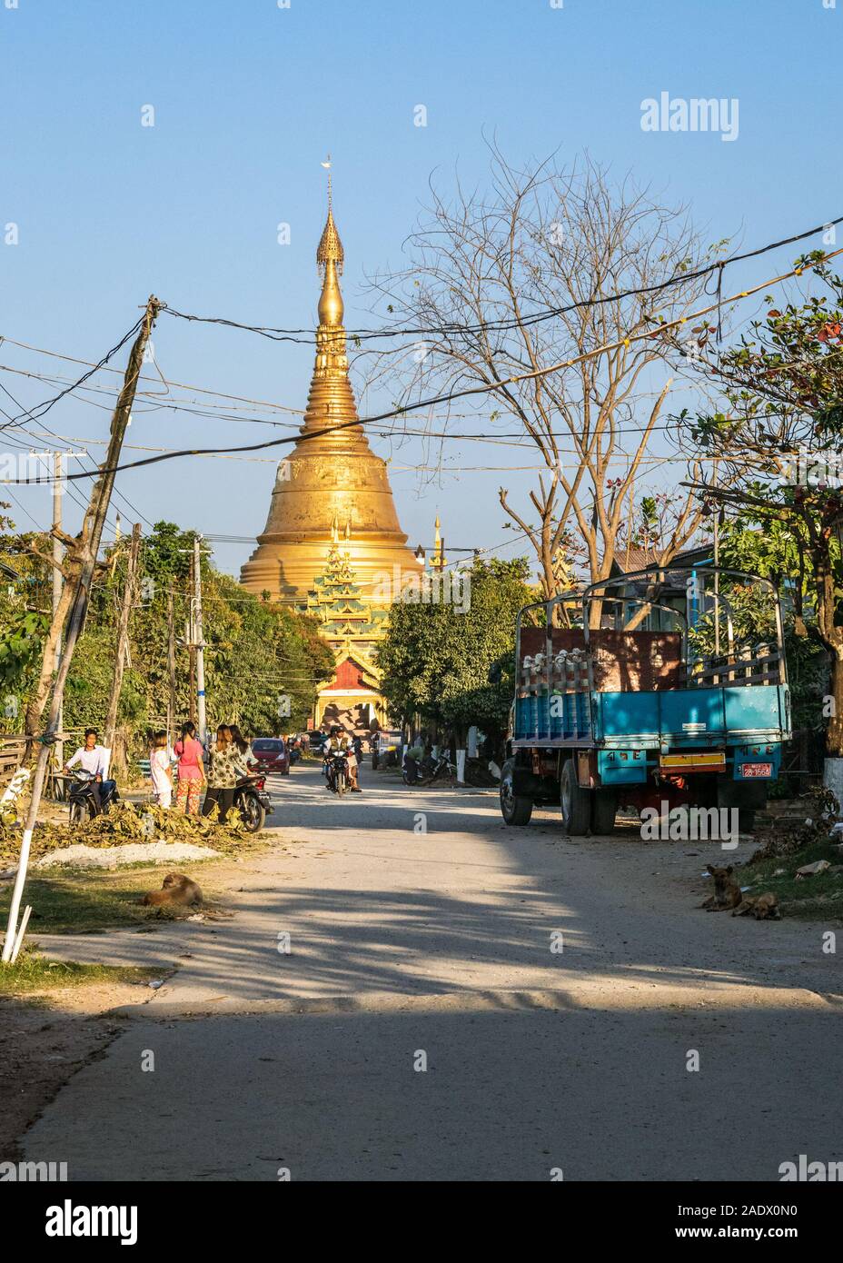 Local people going about their everyday life in a  small burmese town of Taungoo, Myanmar with the famous Swesandaw pagoda in the background. Stock Photo