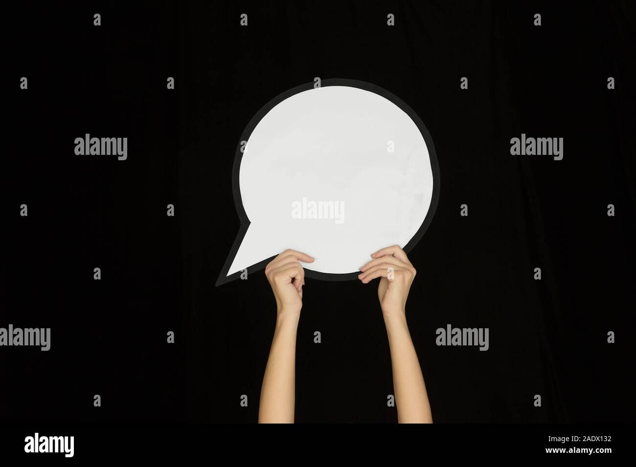 Hands holding the sign of comment on black studio background. Negative ...