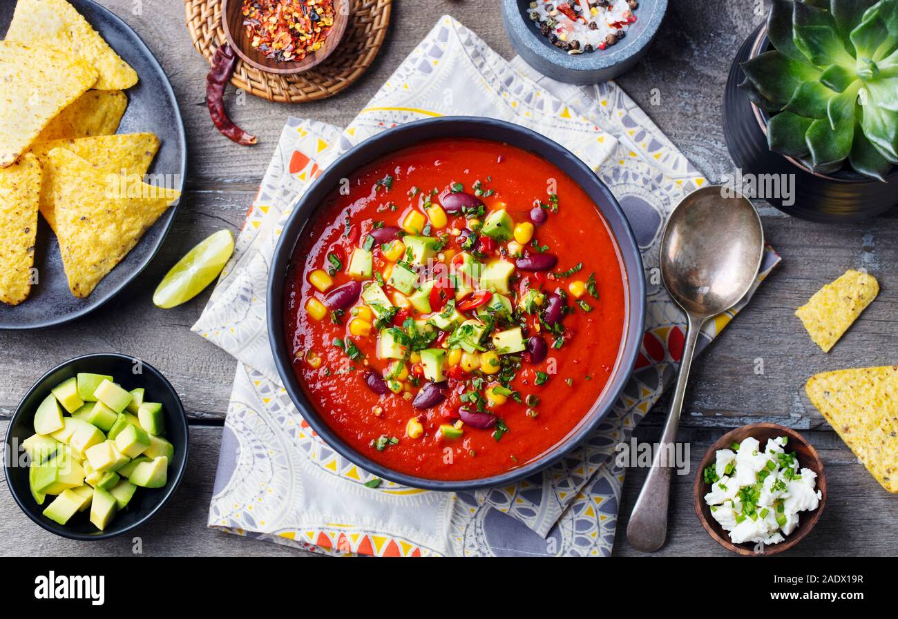 Mexican tomato, bean, bell pepper soup in black bowl. Top view Stock Photo