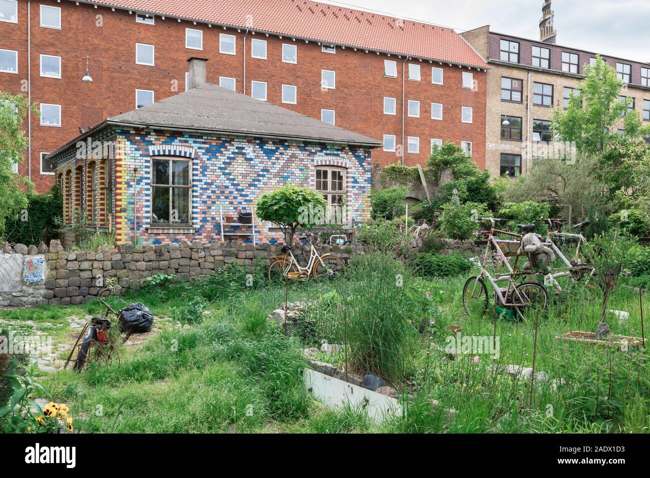Christiania Copenhagen, view of a colorful tiled building, garden and abandoned bicycles in the alternative Freetown area of Christiania, Copenhagen. Stock Photo