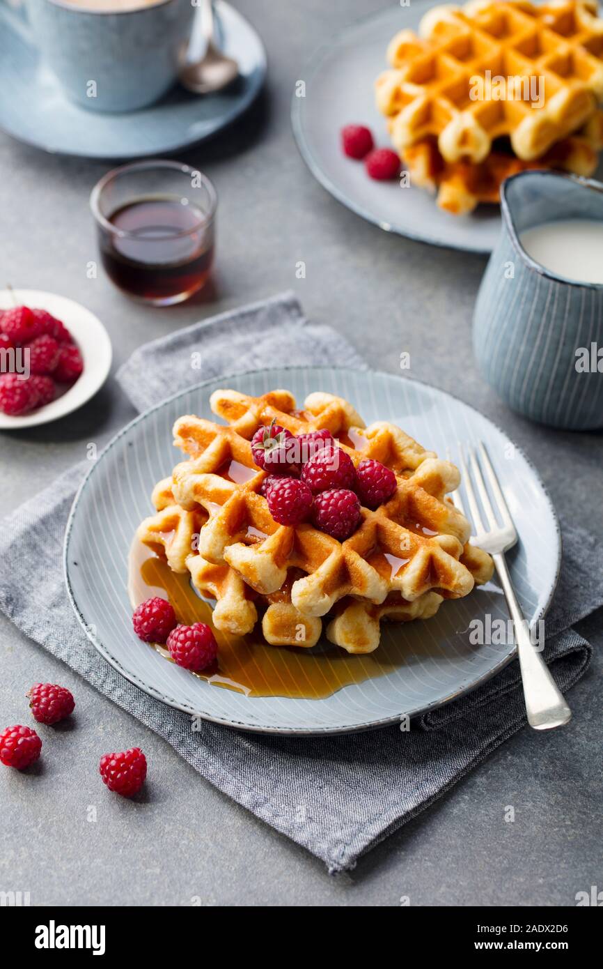 Belgian waffles with maple syrup and fresh raspberry. Grey background