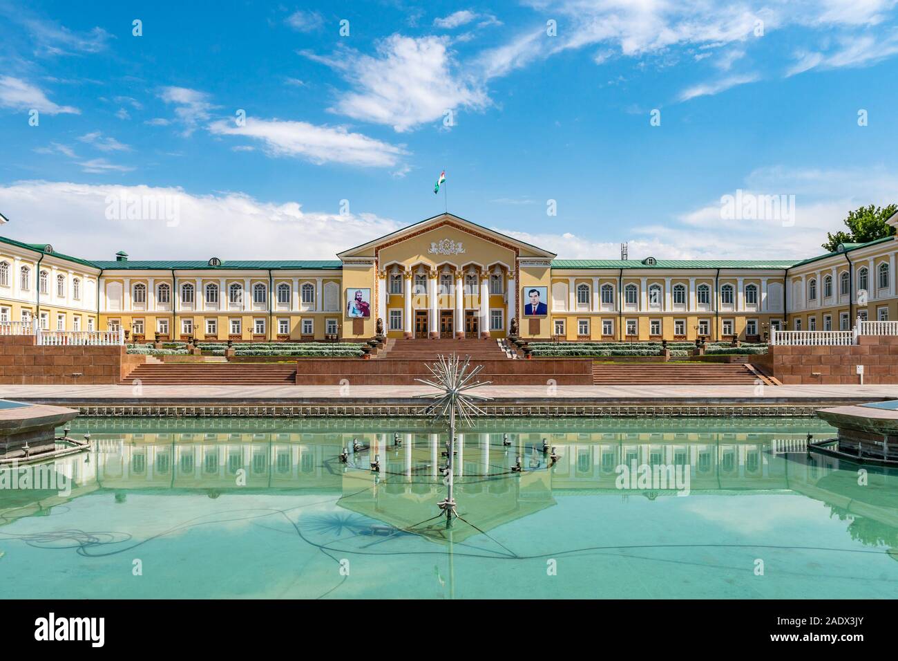 Khujand Arbob Cultural Palace View with Waving Tajikistan Flag and Portraits of Ismoil Somoni and President Emomali Rahmon on a Sunny Blue Sky Day Stock Photo