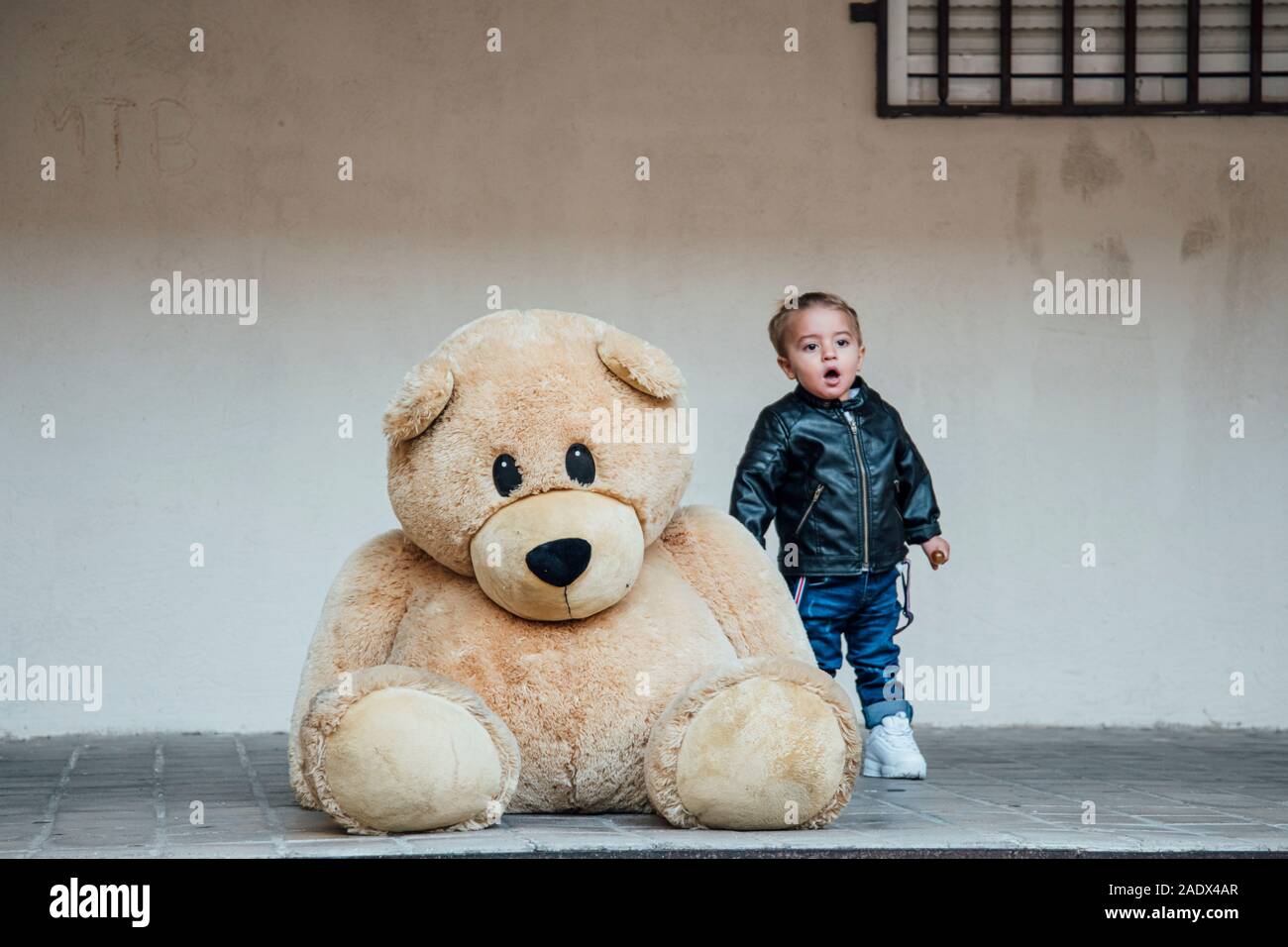A little boy playing with a giant teddy bear Stock Photo - Alamy