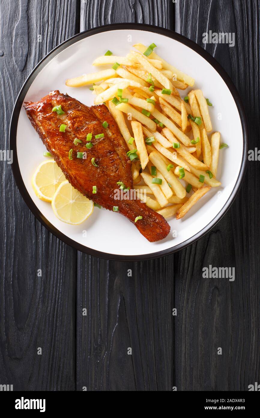 Main dish fried rockfish served with French fries close-up in a plate on the table. vertical top view from above Stock Photo