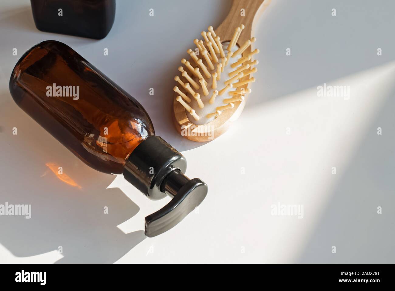 Shampoo in glass bottle and wooden hair brush on the table with