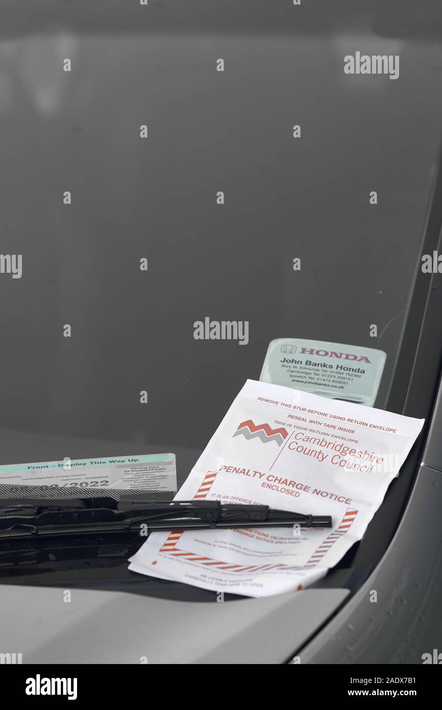 Penalty charge notice (parking fine) fixed securely under the windscreen wiper of a car in Cambridge, England. Stock Photo