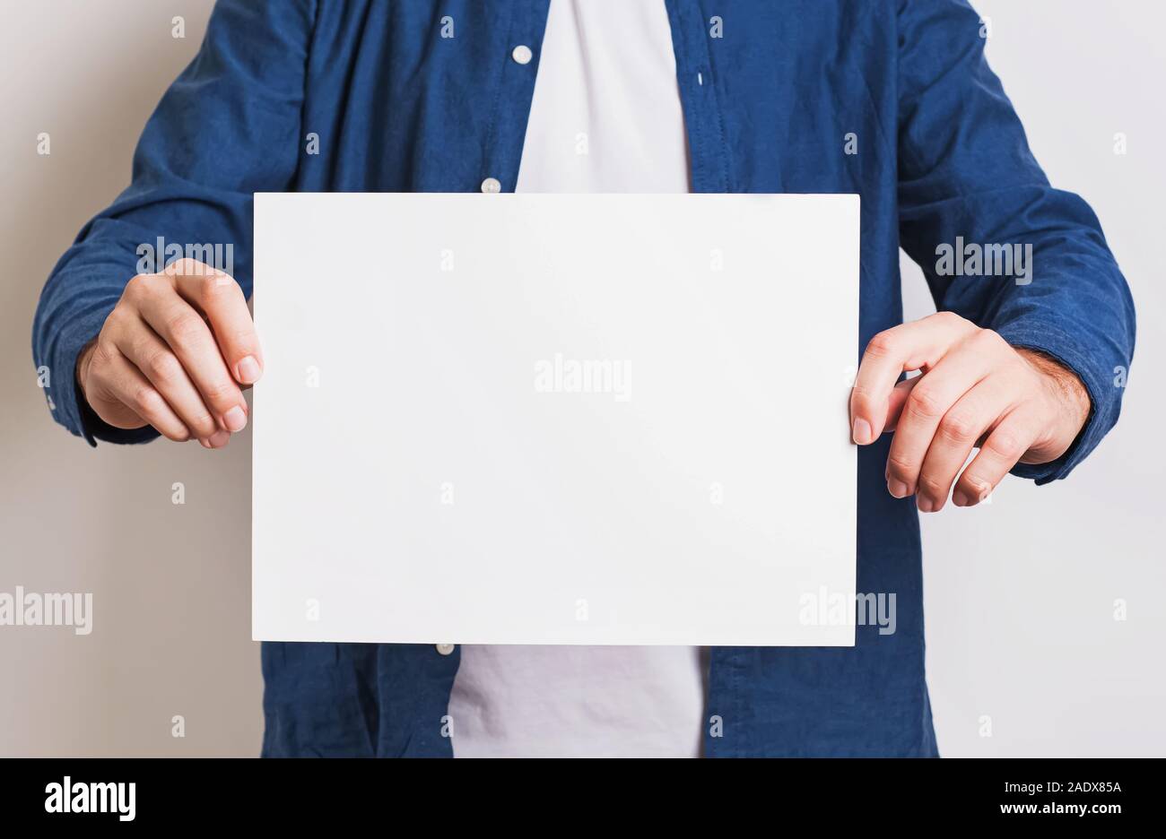 Man in blue shirt holding white blank paper Stock Photo