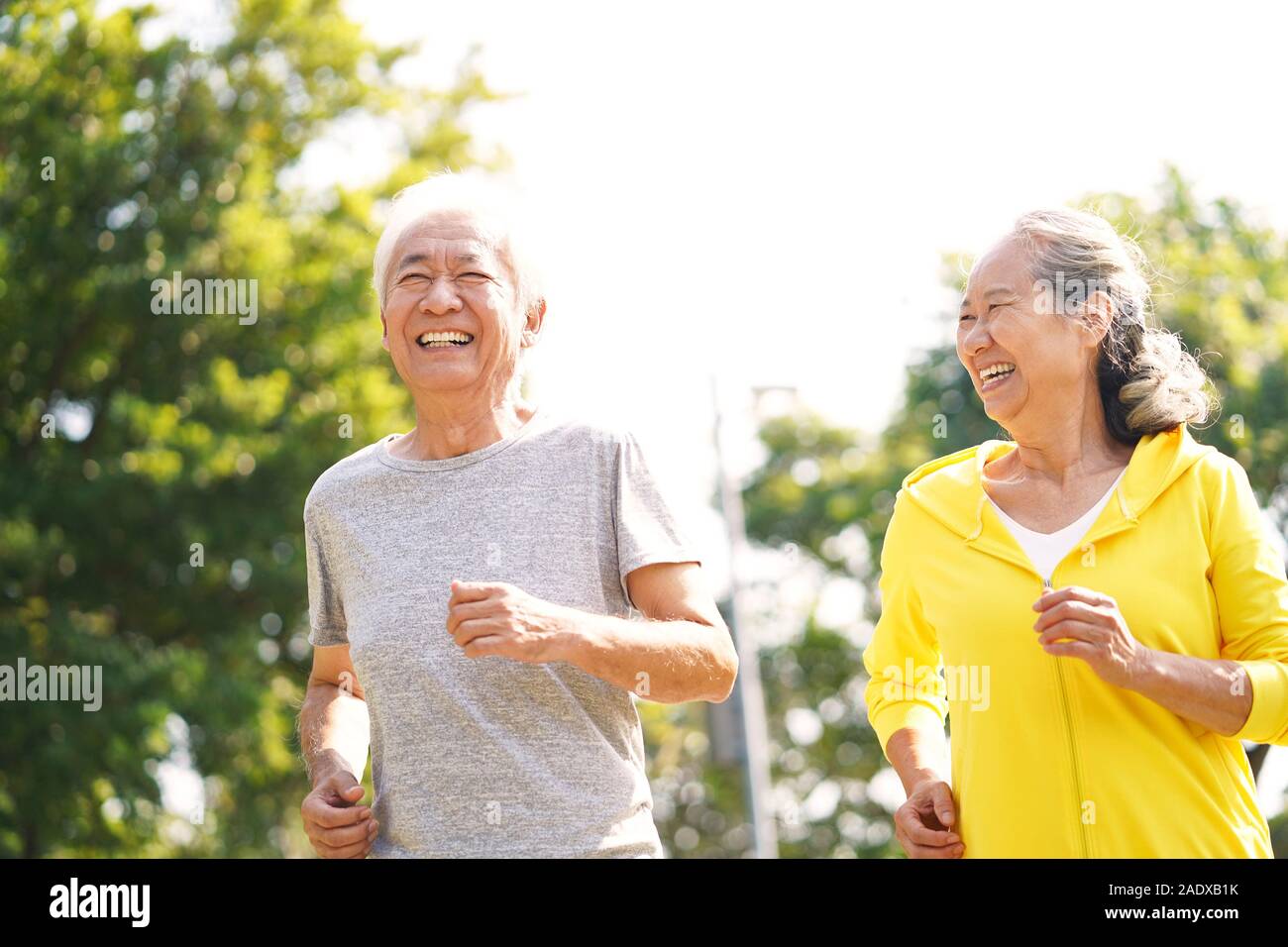 happy asian senior couple running exercising outdoors in park Stock Photo