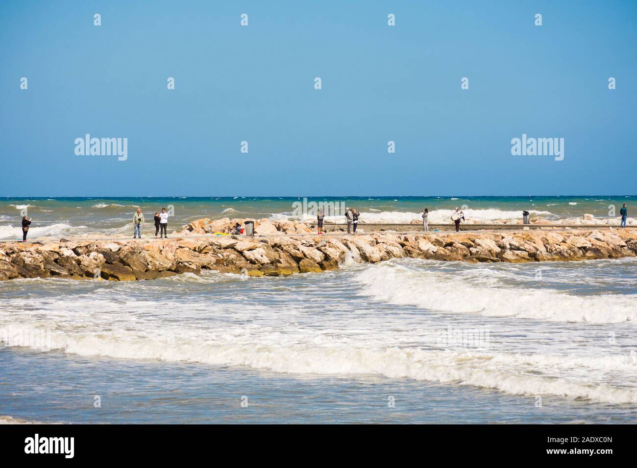 People watch high waves tide and wind on pier, Fuengirola, Malaga, Andalusia. Spain Stock Photo