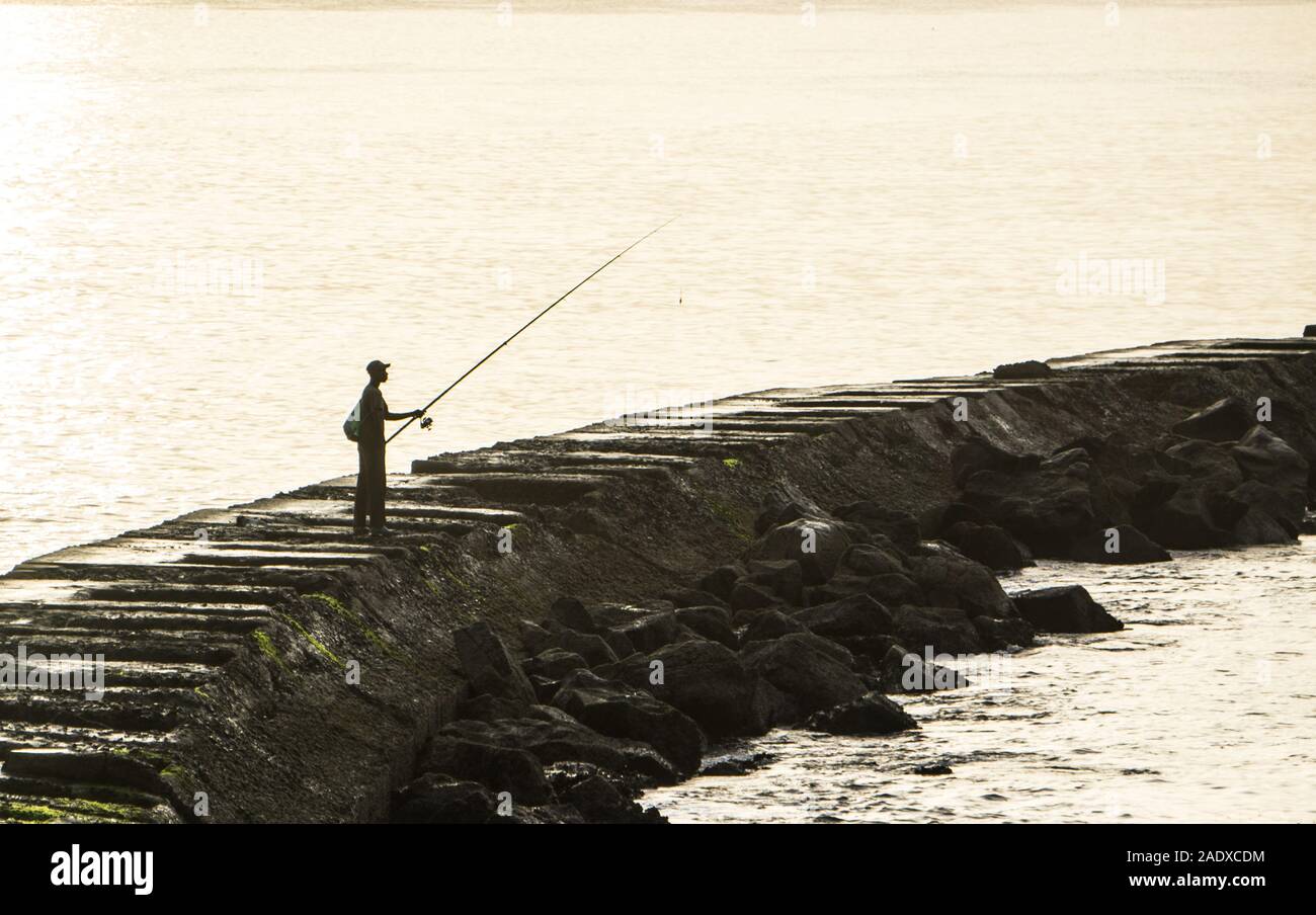 Sun through the morning mist on a lone fisherman in Dakar, Senegal. Stock Photo