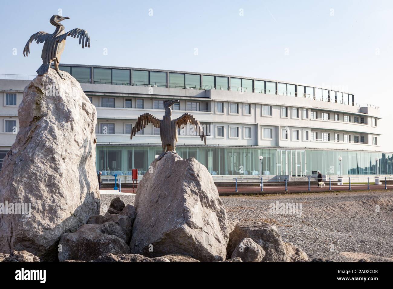 Morecambe Cormorant Sculptures. On the Stone Jetty in the Lancashire seaside town with the promenade and Art Deco Midland Hotel behind. Stock Photo