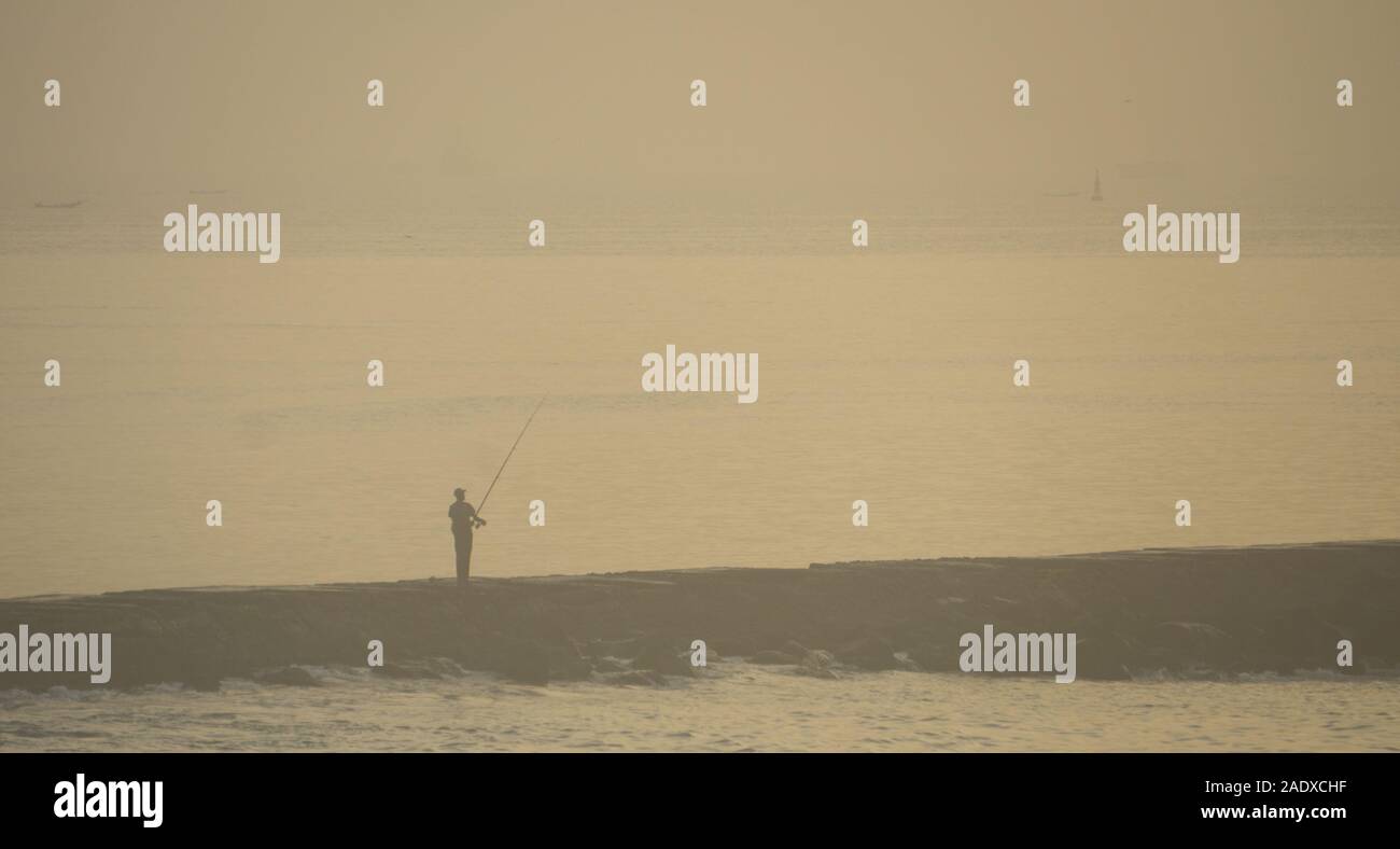 Sun through the morning mist on a lone fisherman in Dakar, Senegal. Stock Photo