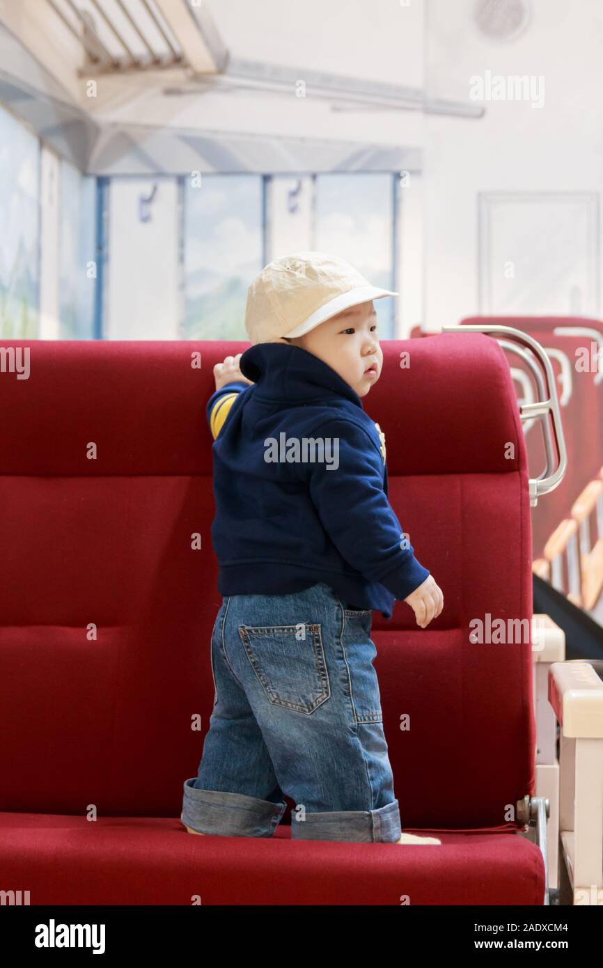 cute korean baby boy standing on the seat in the old train, baby fashion Stock Photo