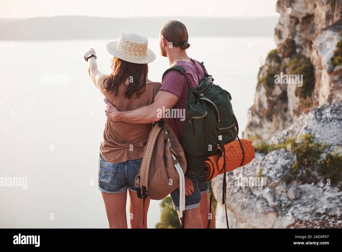Two tourist male and woman with backpacks stand to the top of the crag ...