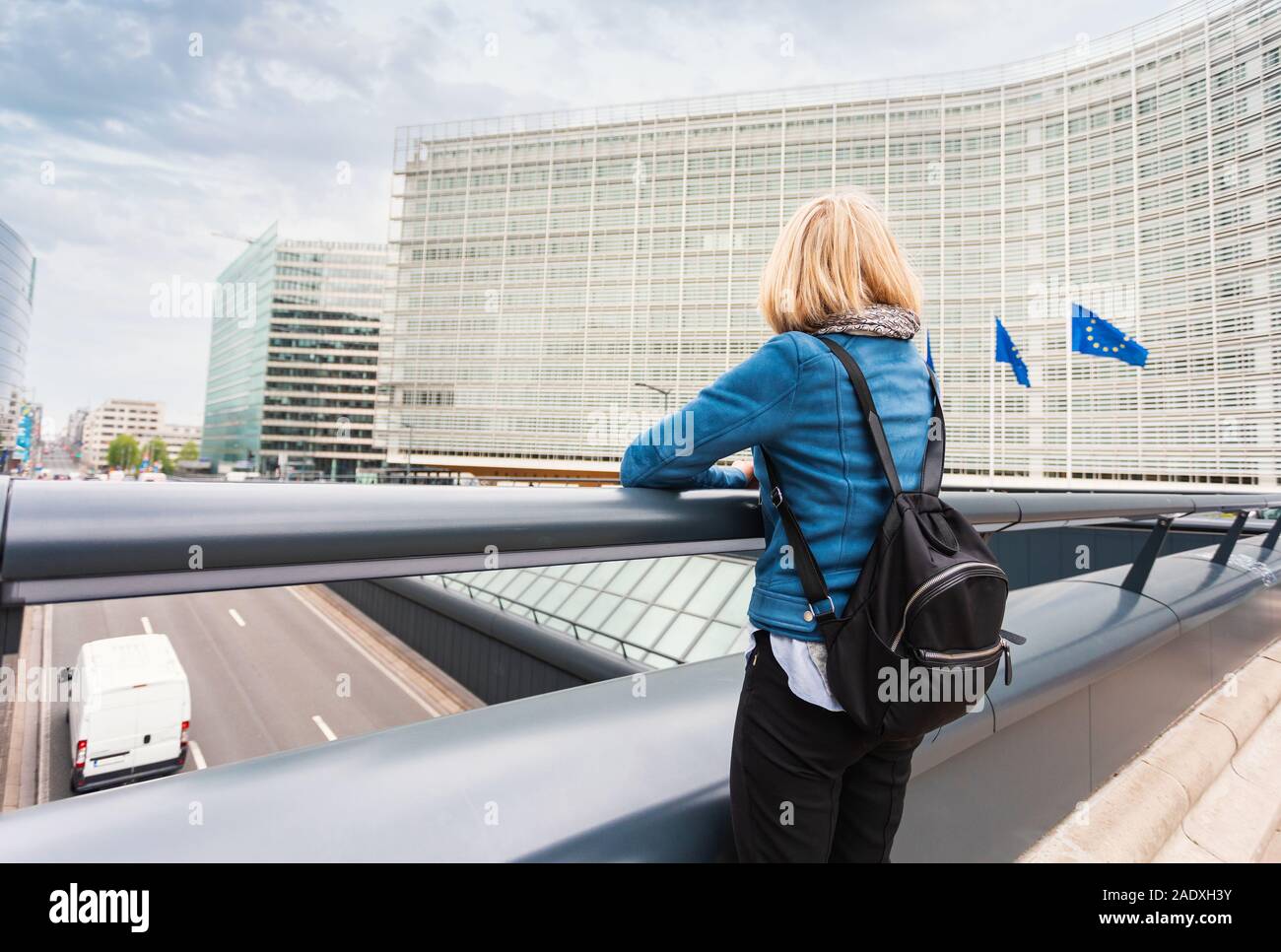 A young woman stands against the backdrop of the European Commission headquarters in Brussels, Belgium Stock Photo