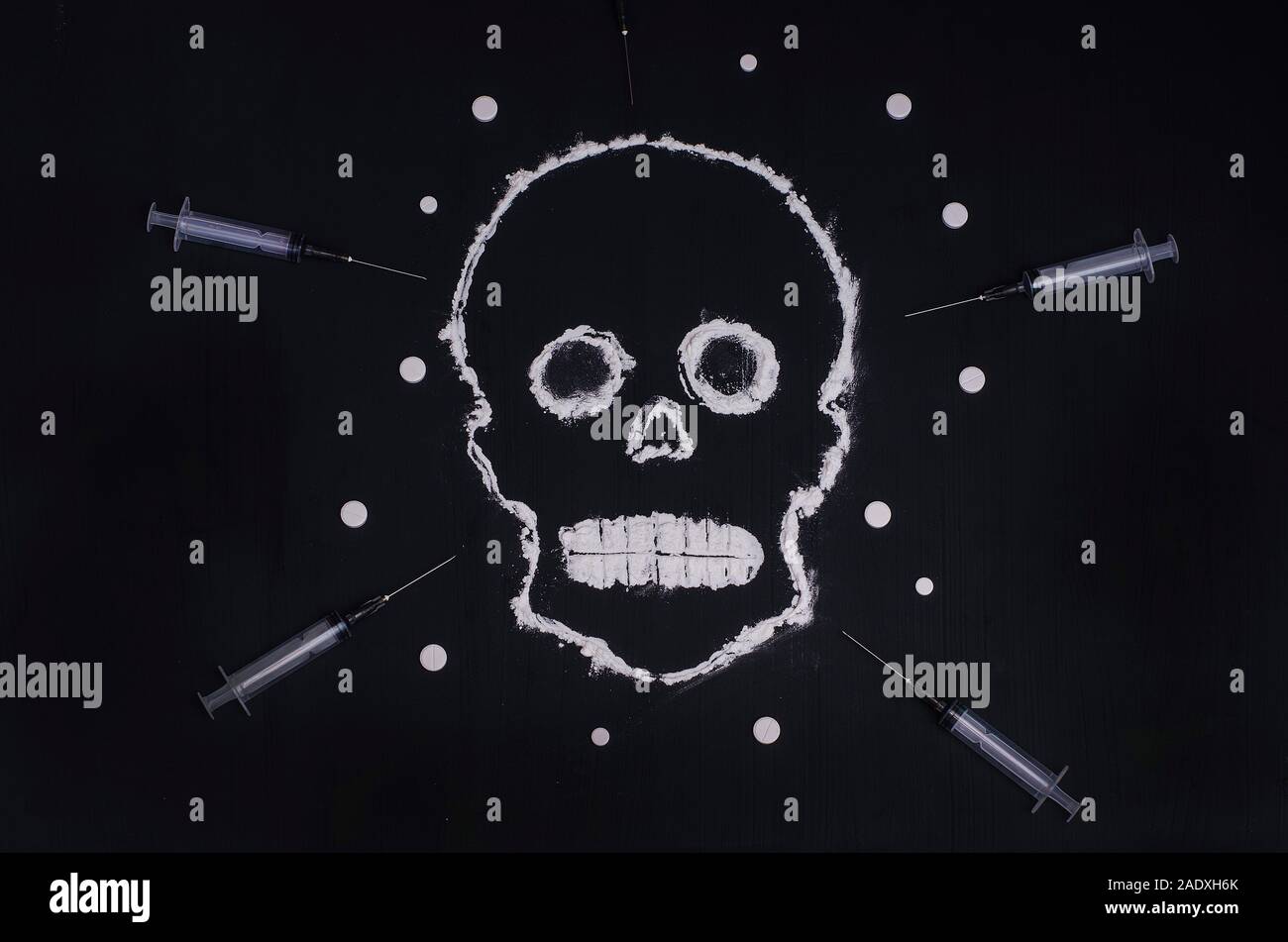 Social advertisement. The concept is death from drugs. Skull made of white powder on a black background with syringes and pills. For young people. Stock Photo