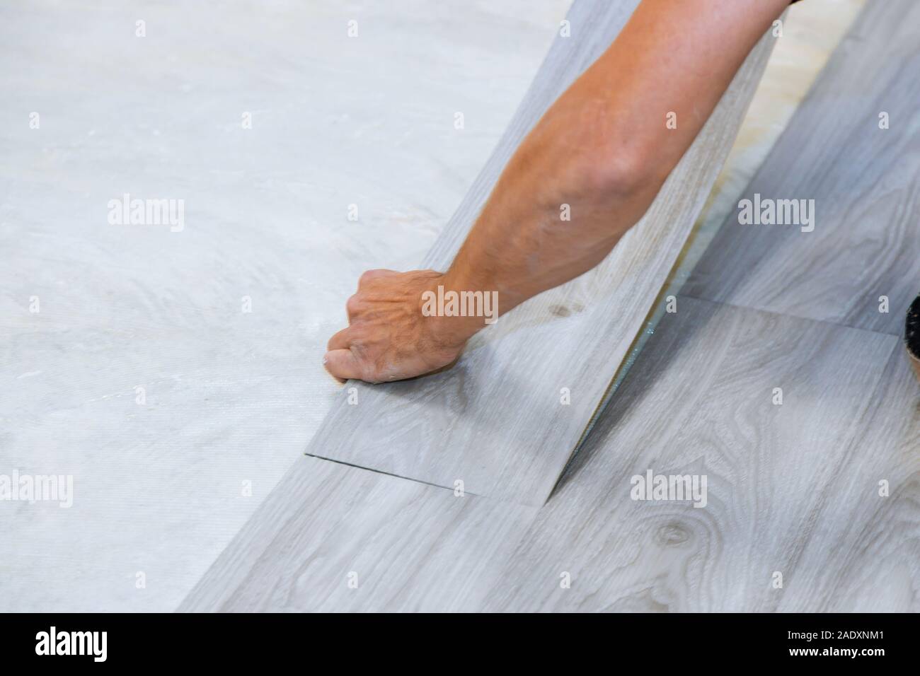 Worker installing new vinyl tile floor with new home improvement laminate wood texture floor Stock Photo