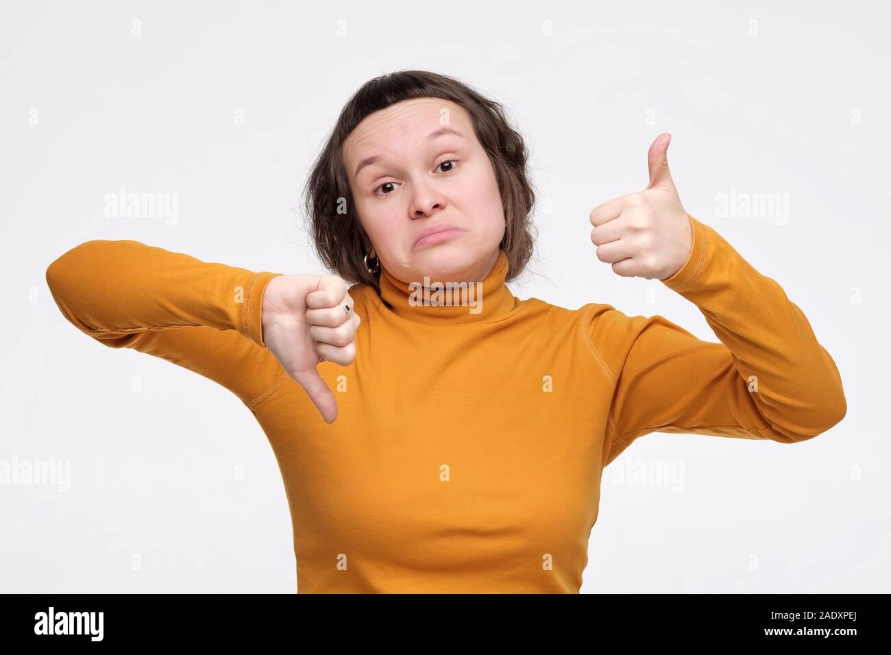Pretty Young Girl Making Good Bad Sign Showing Thumb Up And Down. Studio  Shot Stock Photo - Alamy
