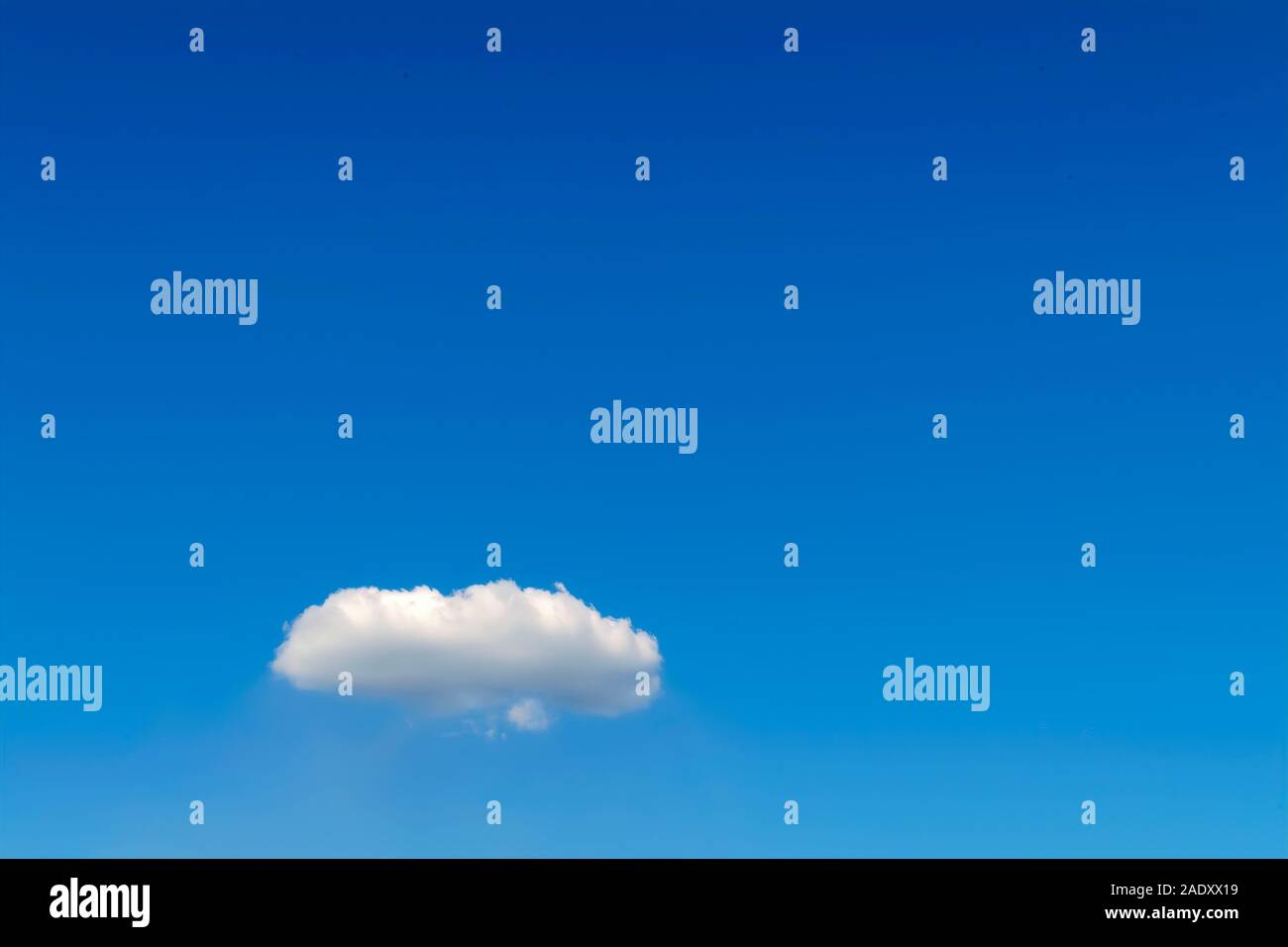 Single white fluffy cumulus cloud against a blue sky. Stock Photo