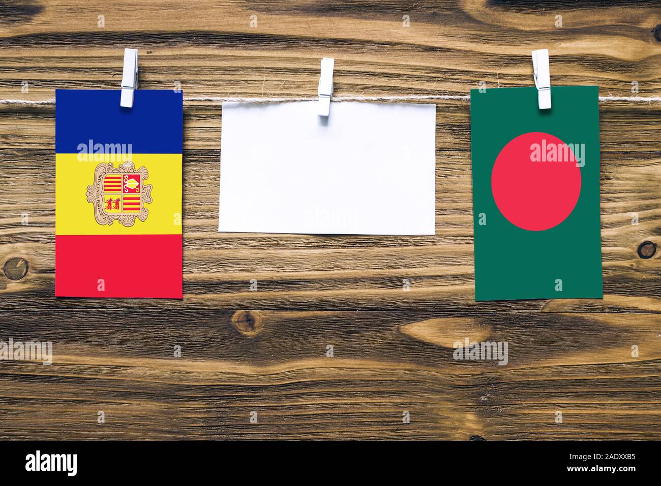 Hanging flags of Andorra and Bangladesh attached to rope with clothes pins with copy space on white note paper on wooden background.Diplomatic relatio Stock Photo