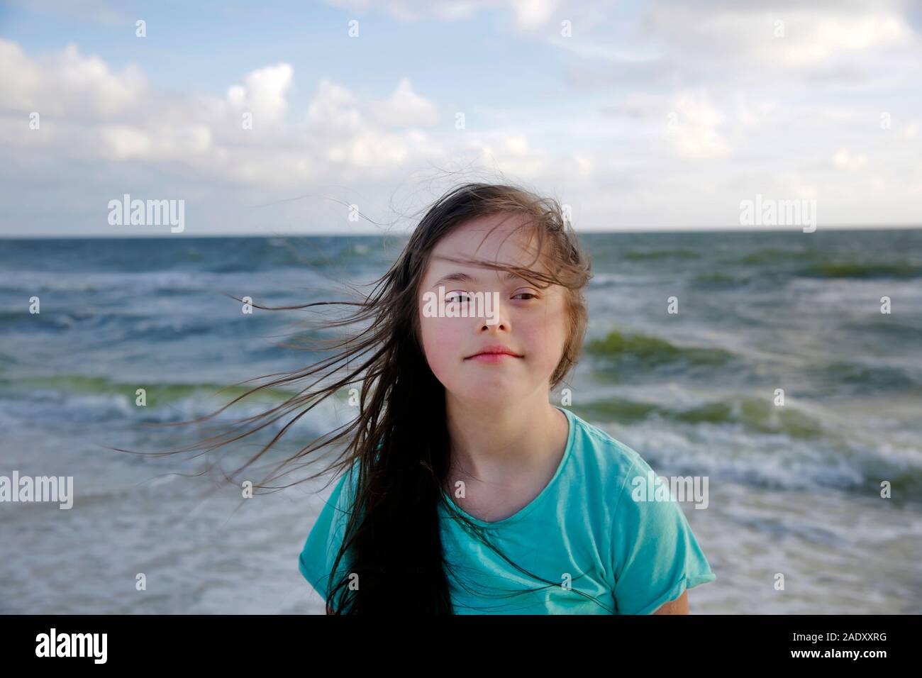 Portrait of down syndrome girl smiling on background of the sea Stock