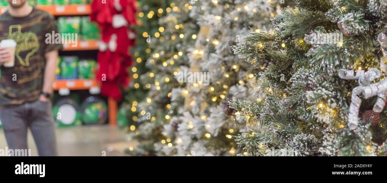 Unidentified man with coffee cup shopping for artificial Xmas tree at hardware store in USA Stock Photo